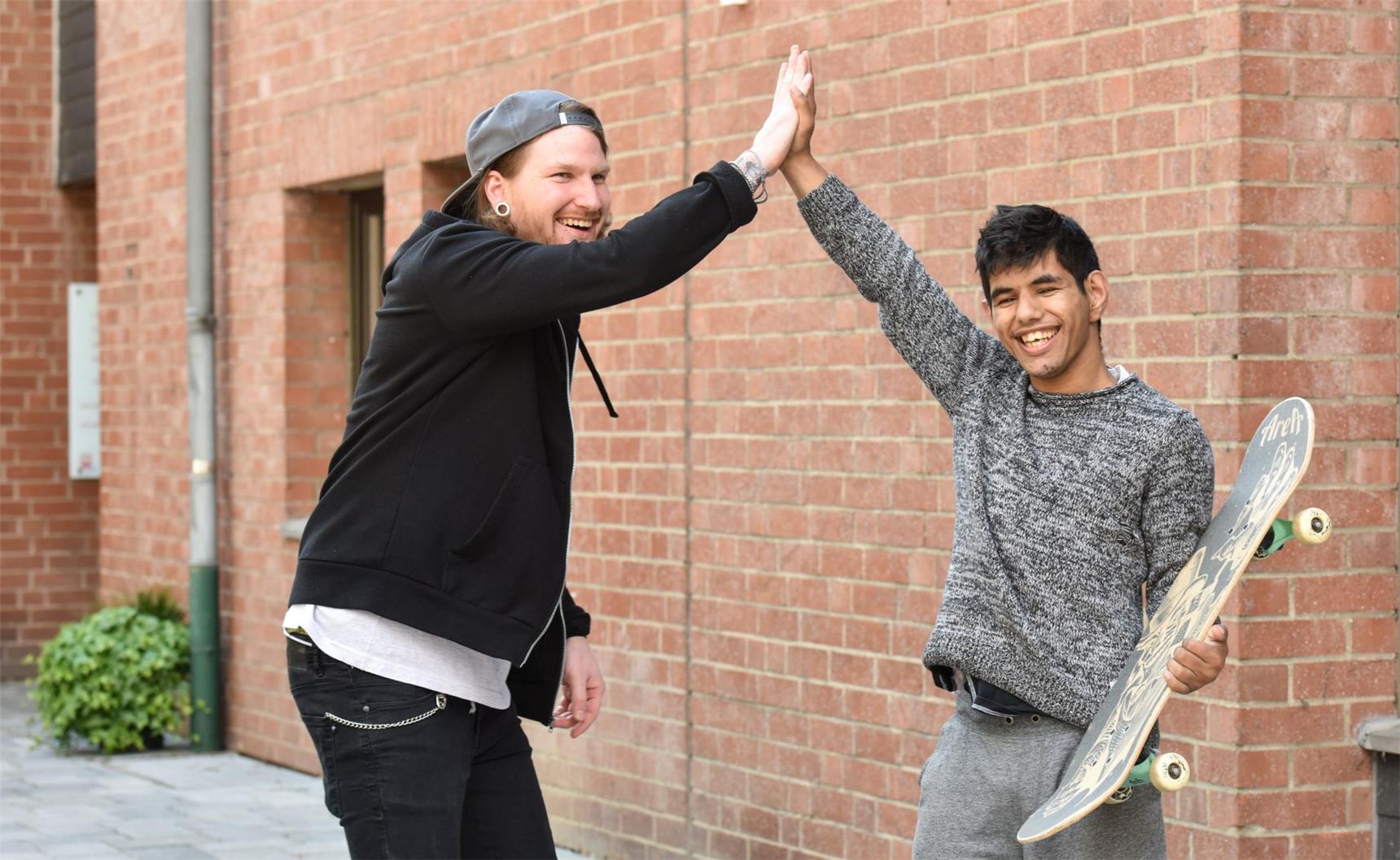 Junge mit Behinderung beim Skateboardfahren mit Freund