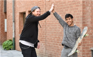 Junge mit Behinderung beim Skateboardfahren mit Freund