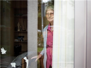 Alte Frau schaut aus dem Fenster.