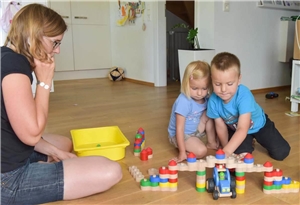Kinder beim Spielen mit Spielzeug. Eine Erzieherin schaut zu.