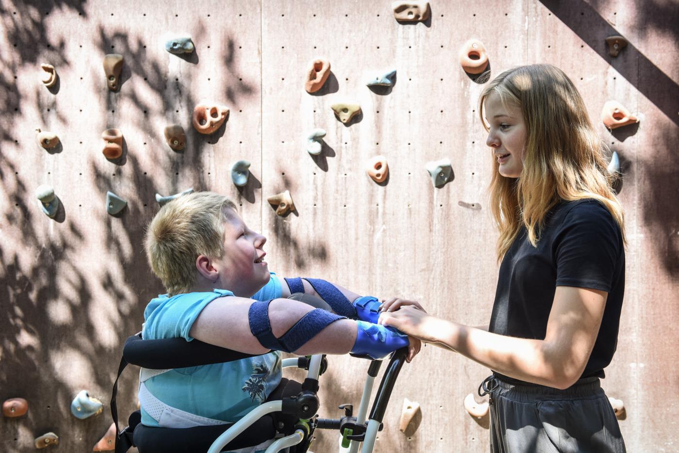 Ein Junge in einer Stehhilfe und eine junge Frau, die seine Hand hält