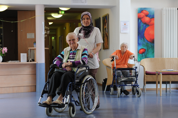 Pflegerin schiebt alte Frau im Rollstuhl