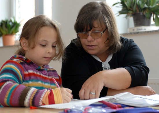 Frau hilft Mädchen bei Schulaufgaben