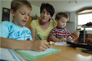 Mutter mit Kindern bei den Hausaufgaben