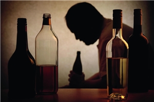 Mann sitzt hinter Flaschen auf einem Tisch