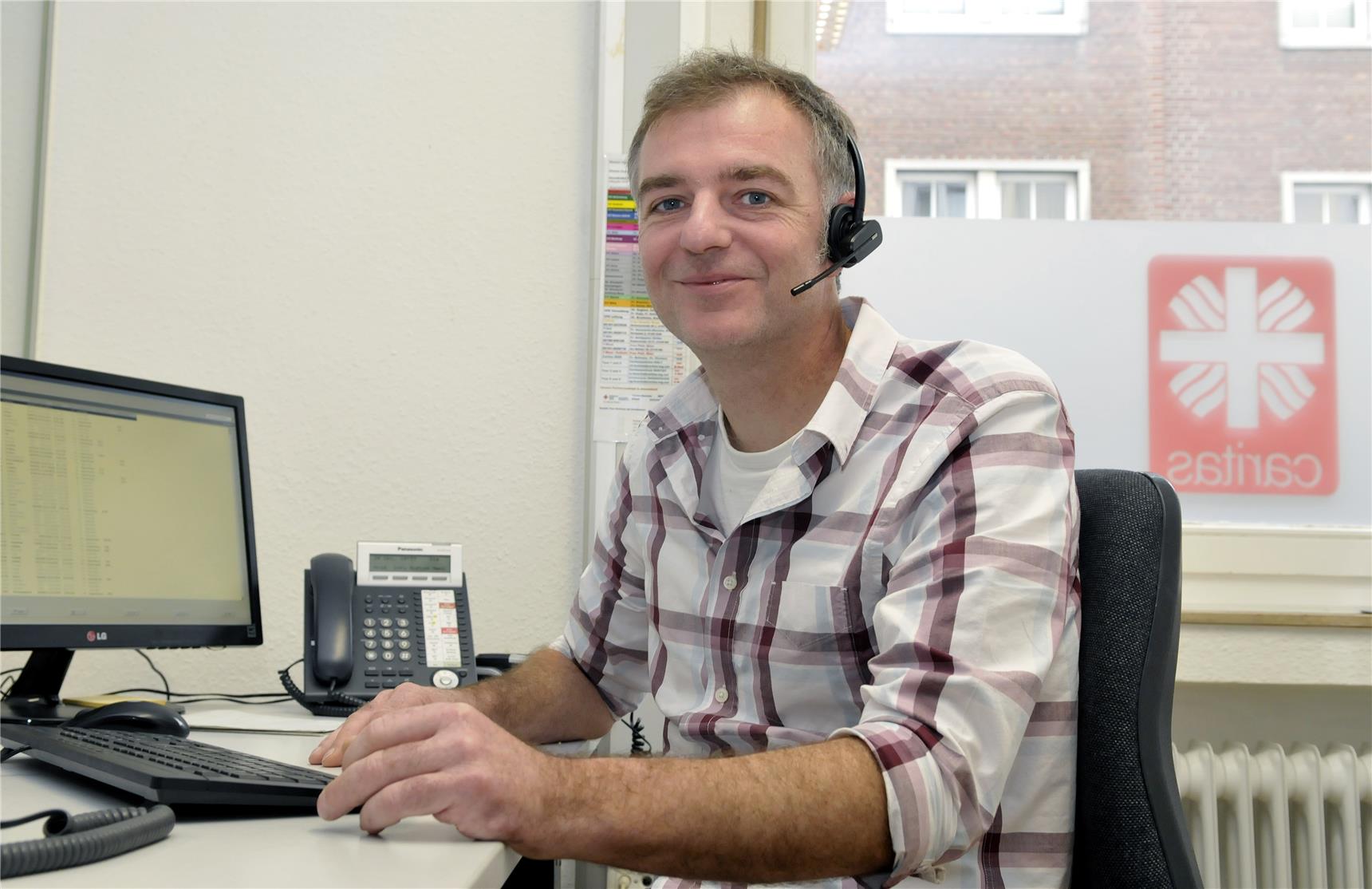 Zentralist des Hausnotrufes mit Headset am Computer