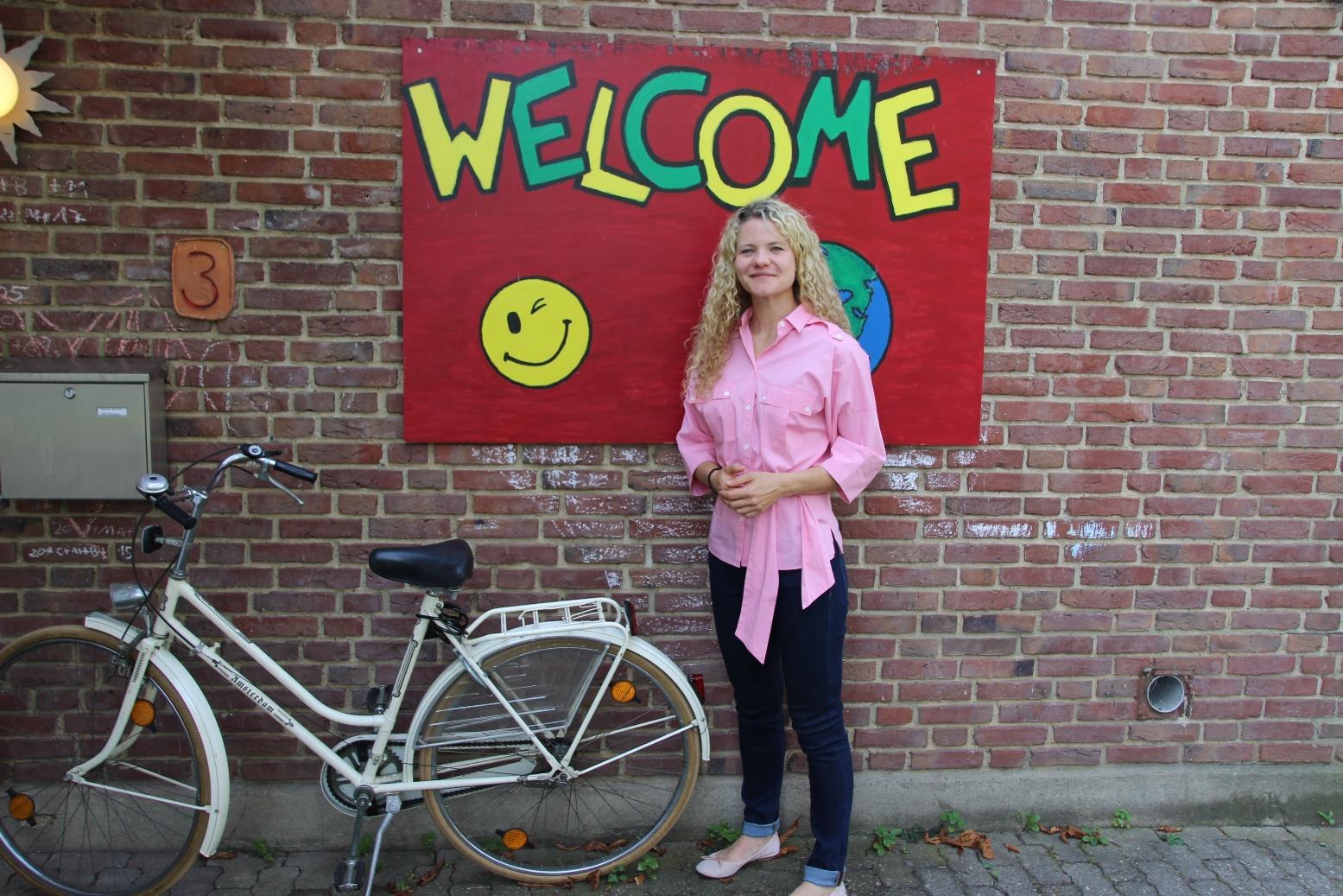 Frau vor auf eine Wand gmaltem Schriftzug 