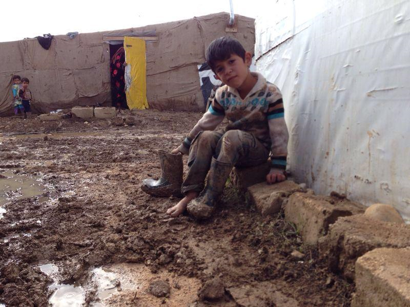 junge sitzt vor einem Zelt in der Nässe