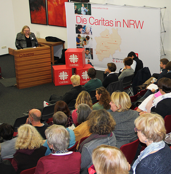 Sabine Depew steht vor einem Pult und hält ihre Begrüßungsrede auf der Fachtagung 'Schon Cross-medial unterwegs?' am 15.09.2017 in  Mülheim an der Ruhr. Im Vordergrund ist das Publikum zu sehen.
