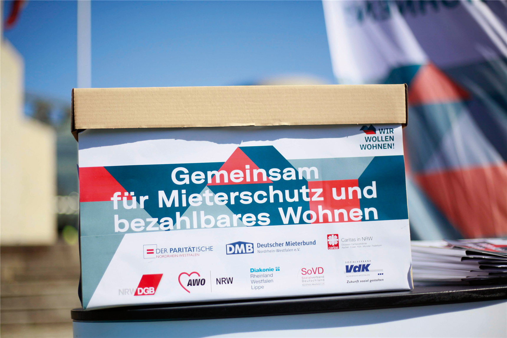 Karton mit Unterschriftenlisten zur Petition des Aktionsbündnisses 'Wir wollen wohnen!'. Der Pappkarton ist außen mit dem Design des Bündnisses beklebt worden.