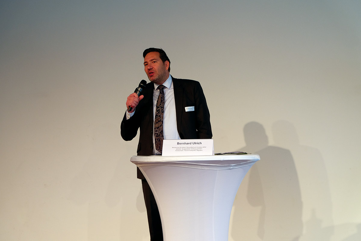 Bernhard Ulrich steht an einem Stehtisch mit einem Mikrofon und hält bei der CiNW-Fachtagung 'Hauptsache Arbeit – oder was? Prekäre Beschäftigung in NRW' am 21.09.2021 in Essen eine Rede