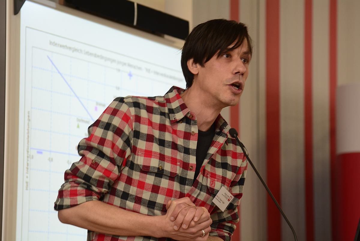 Prof. Dr. Holger Ziegler steht bei der Fachtagung 'Ambulante Hilfen zur Erziehung zwischen Wirksamkeit und Kostendruck' der Caritas in NRW vor einem Pult und hält eine Rede