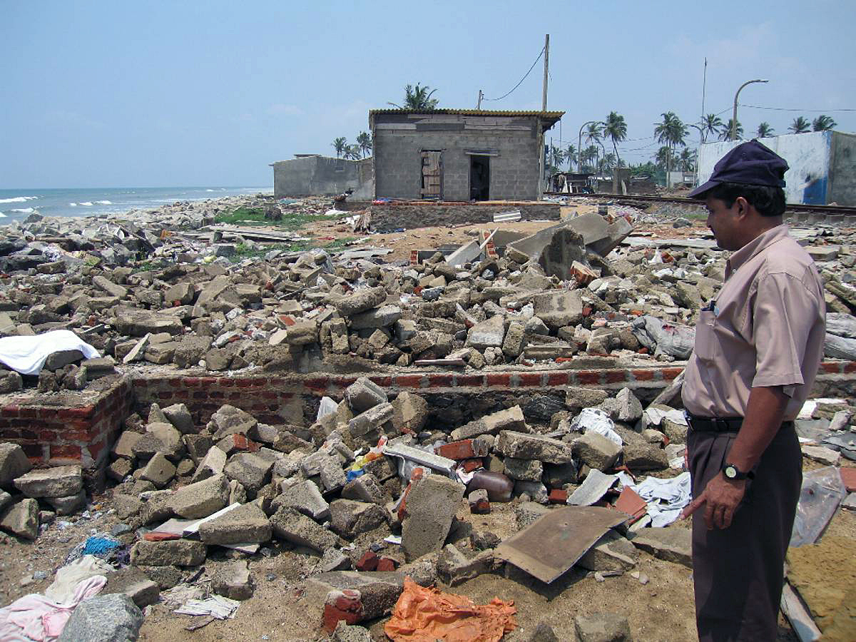 Ein Mann steht nach der Tsunami-Katastrophe vor den Trümmern eines Gebäudes