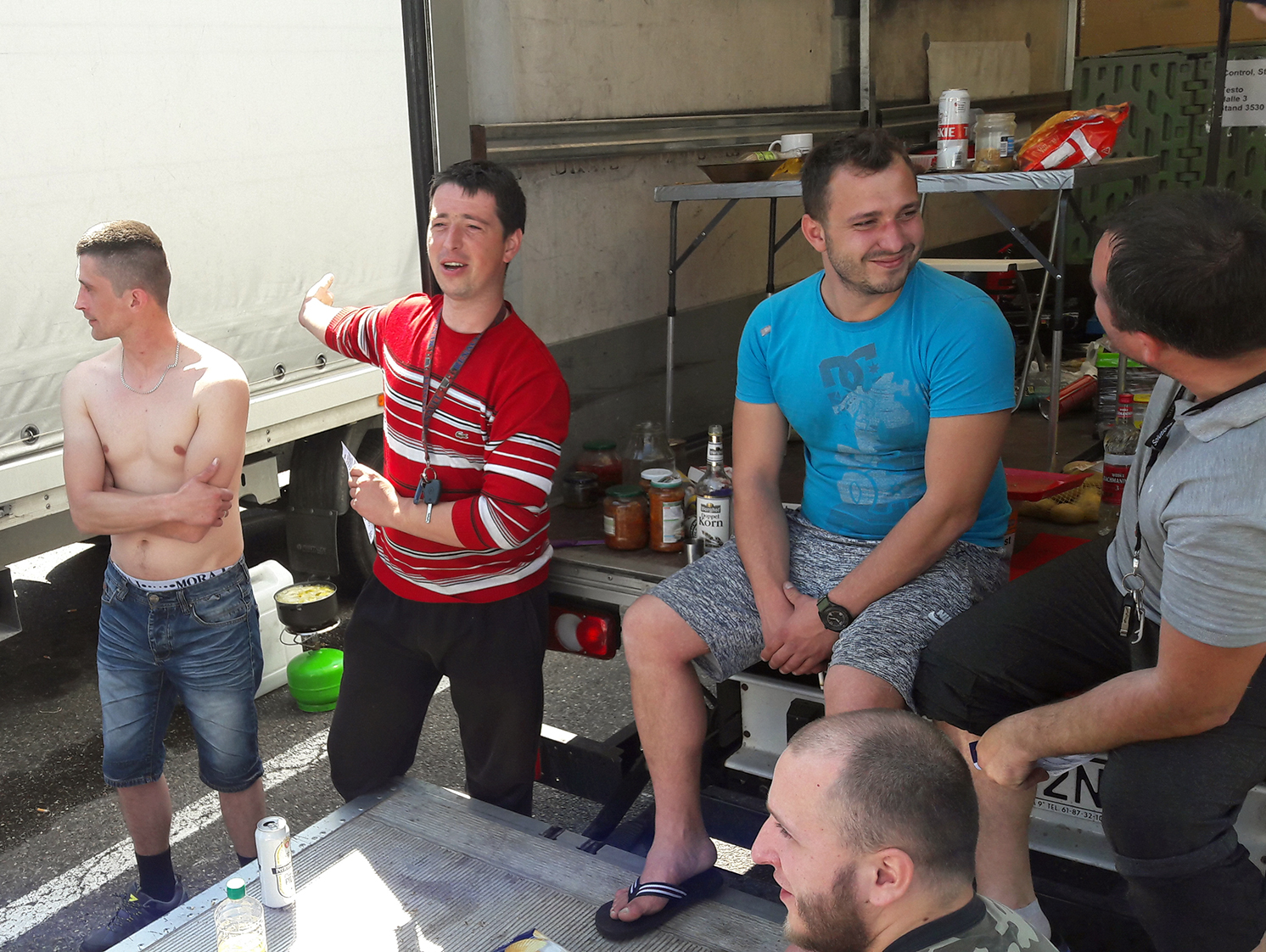 Kleine Gruppe von Fernfahrern im Gespräch vor ihren LKWs