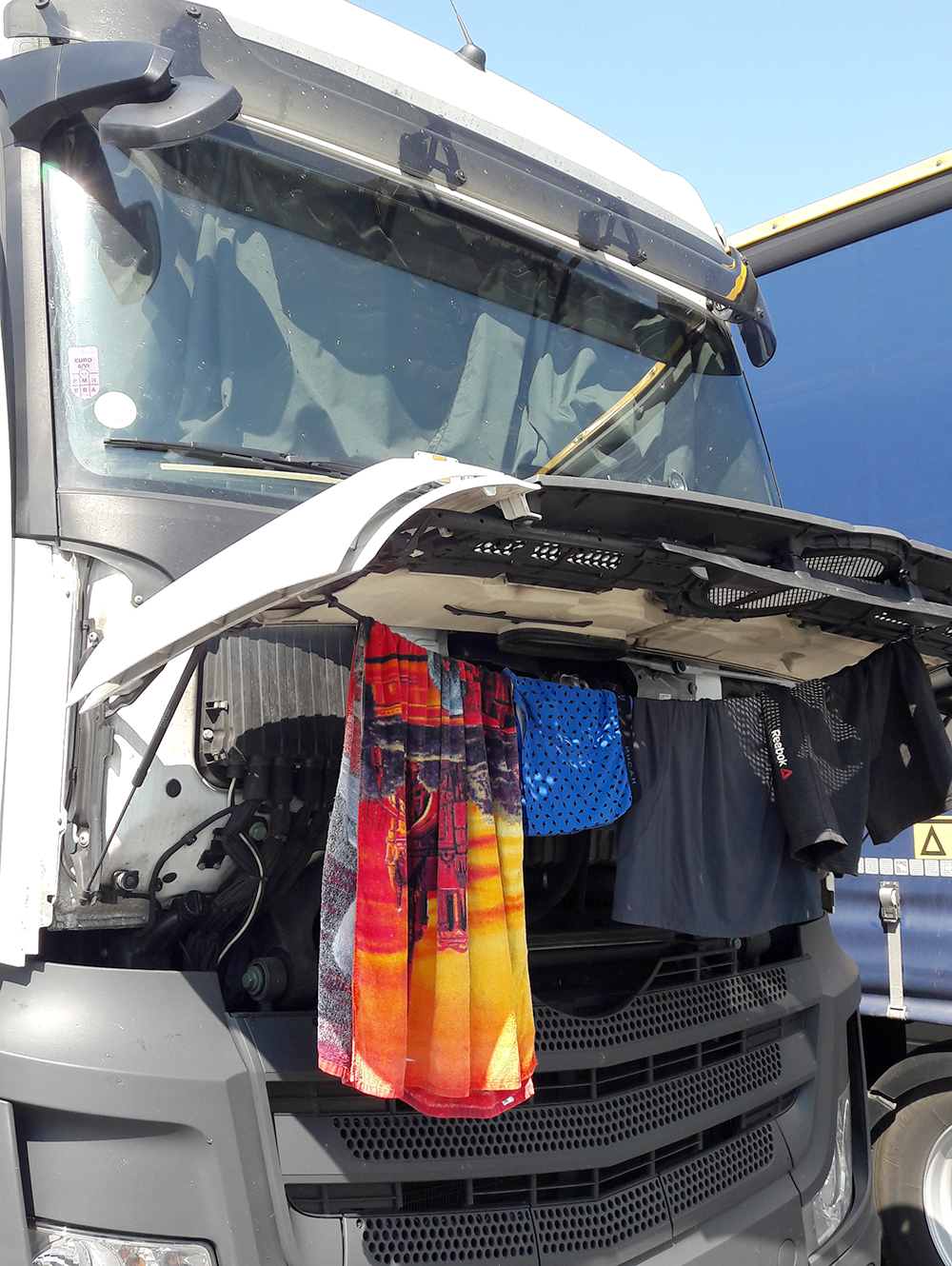 Wäsche hängt zum Trocknen an Motorhaube von LKW.