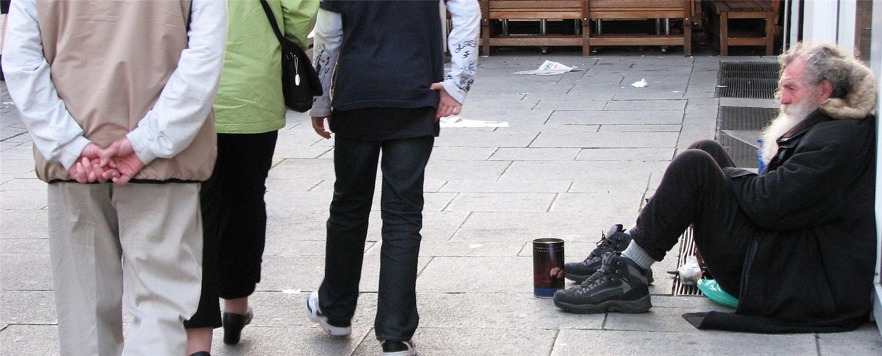 Mann sitzt bettelnd am Straßenrand