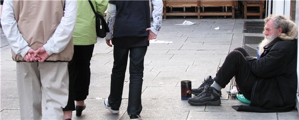 Mann sitzt bettelnd am Straßenrand