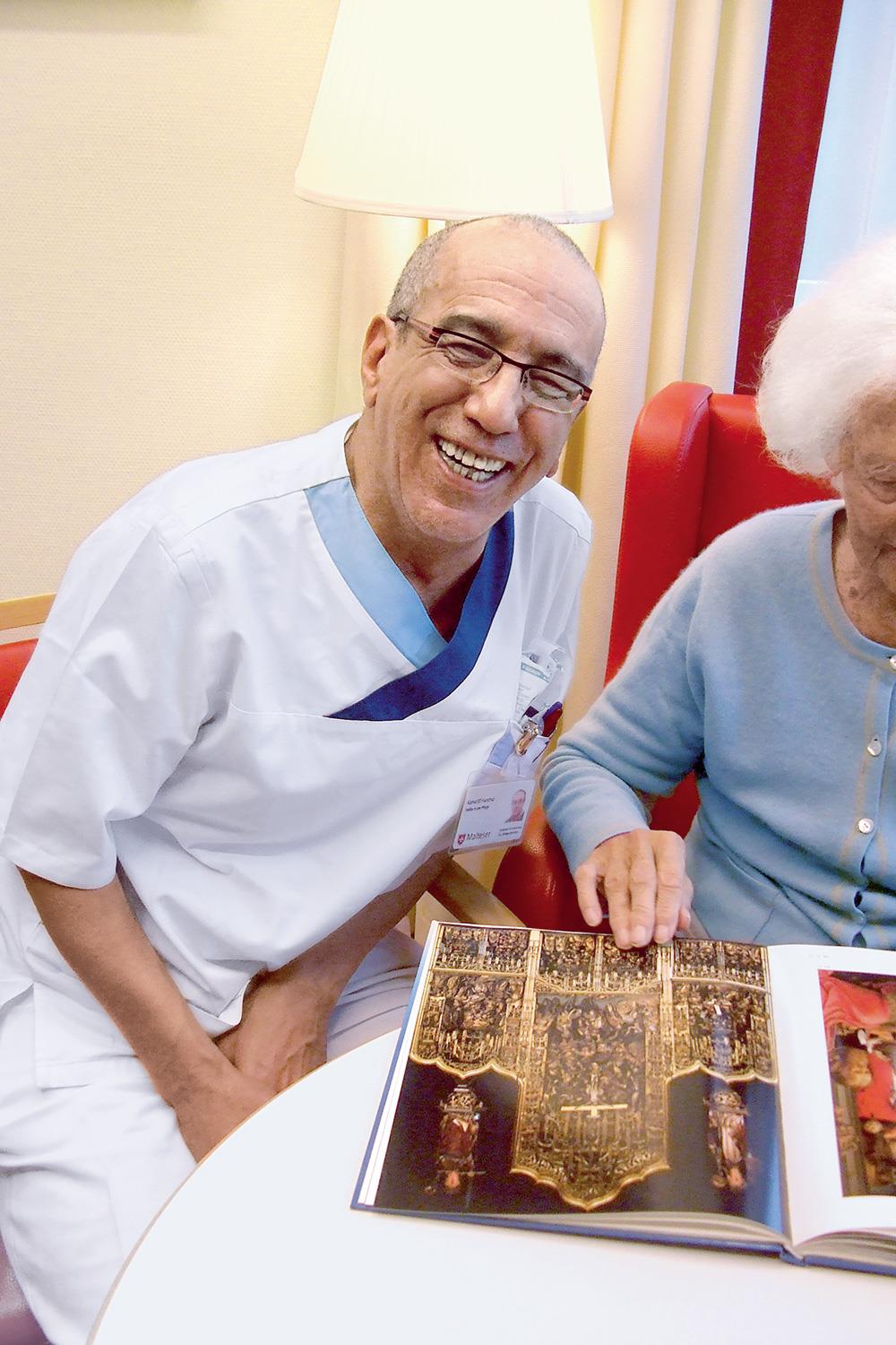 lachender Mann in weißer Kleidung mit Seniorin