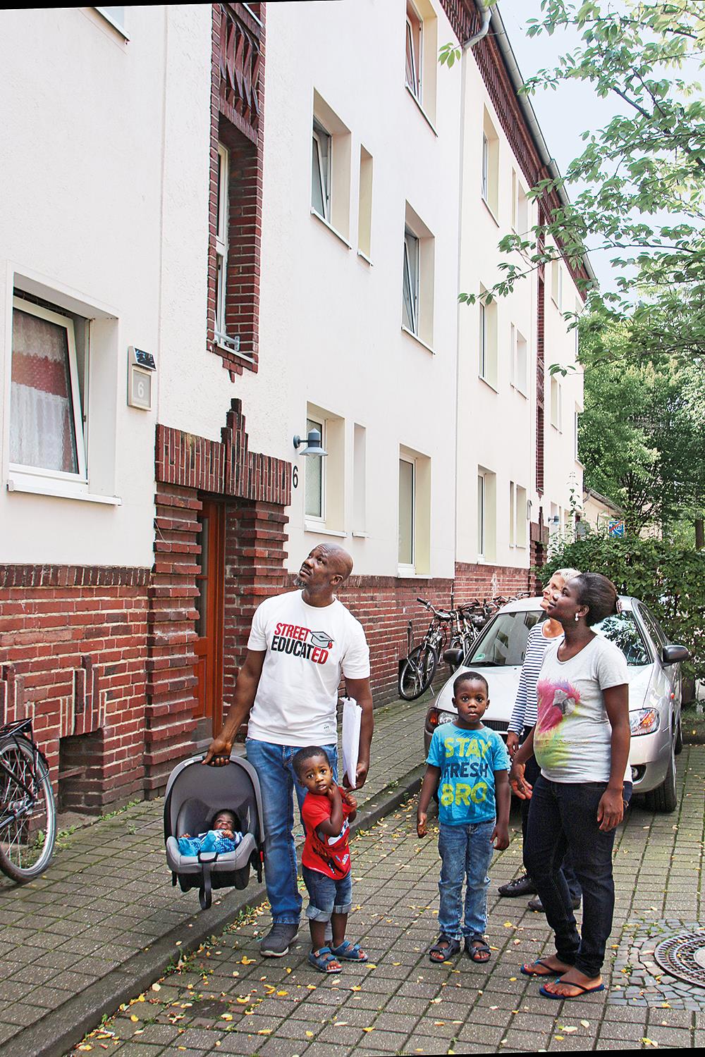 Familie mit Kleinkindern blickt auf Haus.