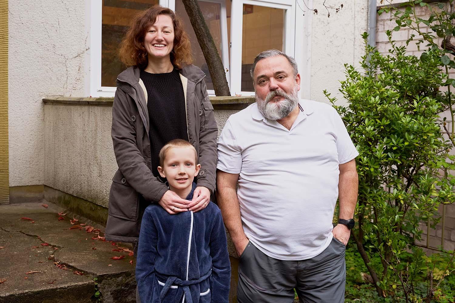 Eine Frau mit einem Kind lacht. daneben steht ein Mann.