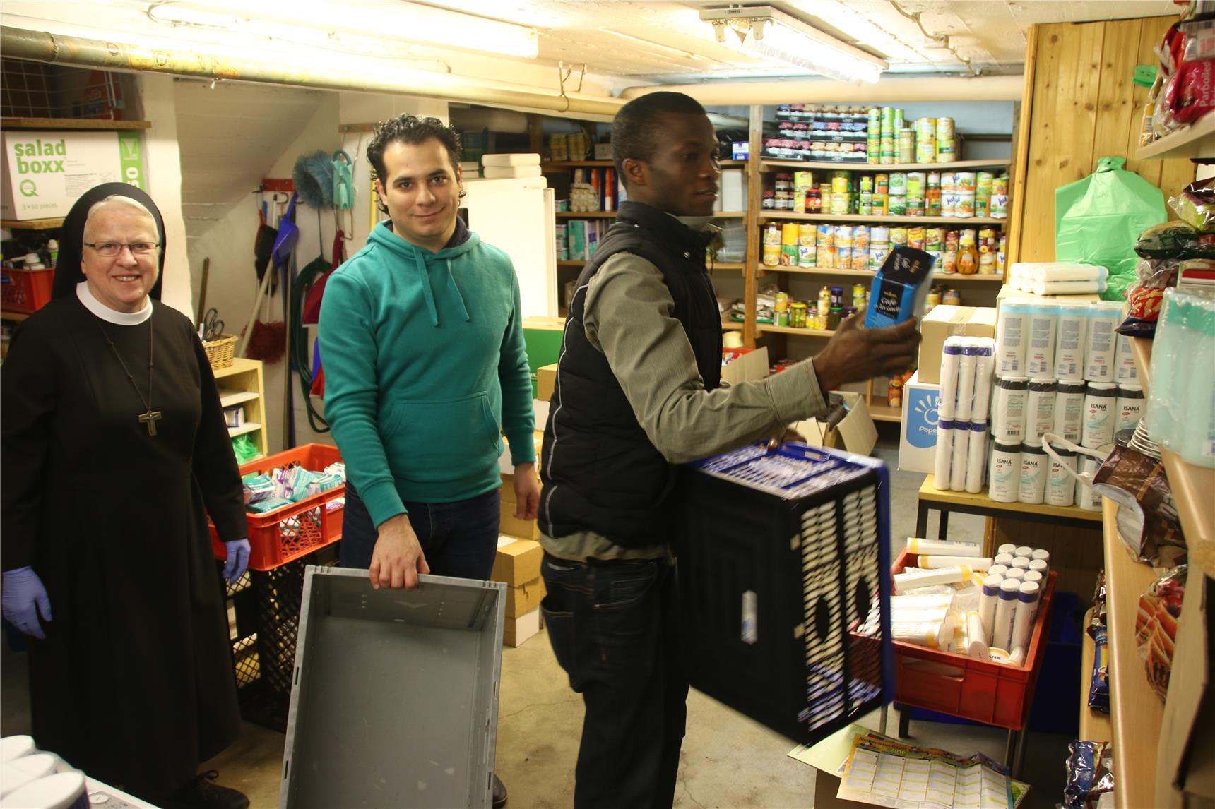 Auf dem Bild stehen drei Menschen in den Räumen einer Tafel