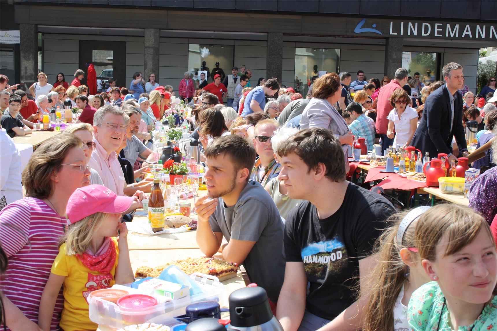 An lagen Tafeln sitzen viele Menschen