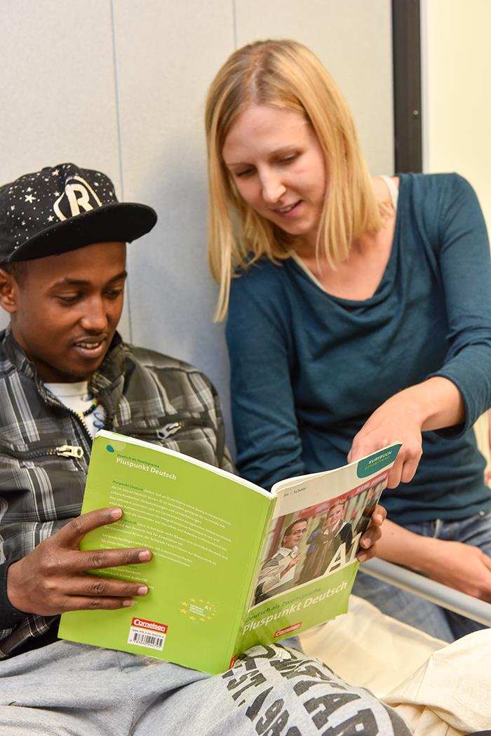Frau hilft jungem Flüchtling beim Deutschlernen