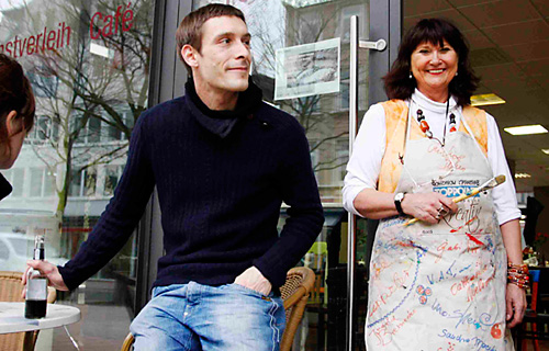 Ein Mann und eine Frau in Arbeitskleidung vor dem Bürgercafé