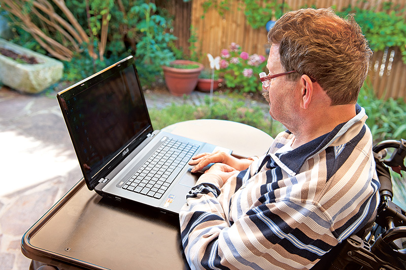 Rollstuhlfahrer Herr Schmitt kommuniziert mithilfe eines Laptops.