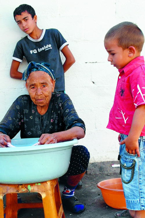 Alte Roma-Frau mit zwei Kindern an Waschzuber